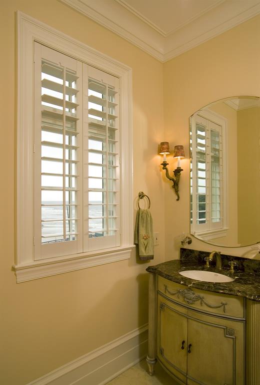 White plantation shutters in a light bathroom looking out over ocean